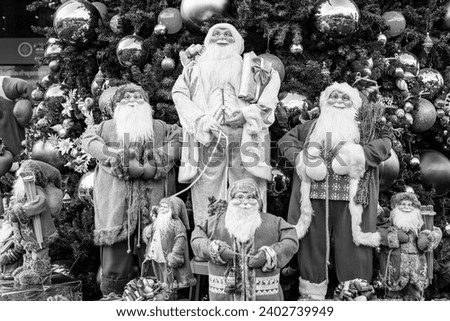 Santa in group in front of beautiful christmas tree decorative with chritmas toys, balls and gifts box in black and white image.