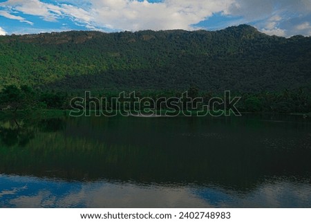 A calm and silent evening at sunset at a small forest lake in Sri Lanka. The lake is surrounded by hills          