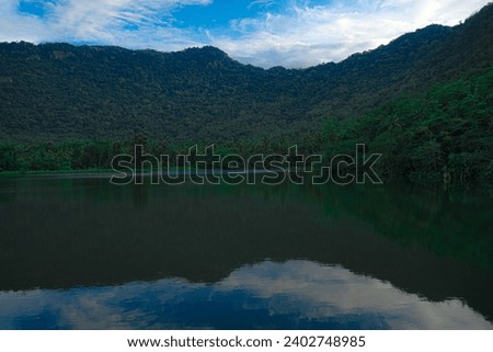 A calm and silent evening at sunset at a small forest lake in Sri Lanka. The lake is surrounded by hills          