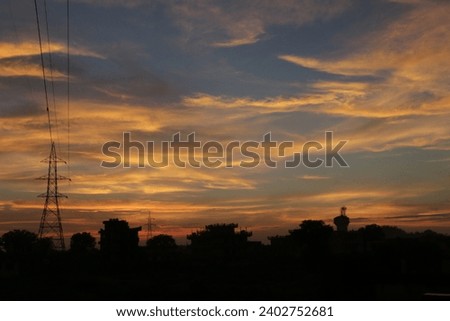 A silhouette, picture taken at twilight highlighting clouds and pylon with cables 