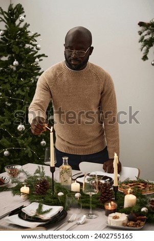 Medium full shot of african american christmas party host lighting candle with match