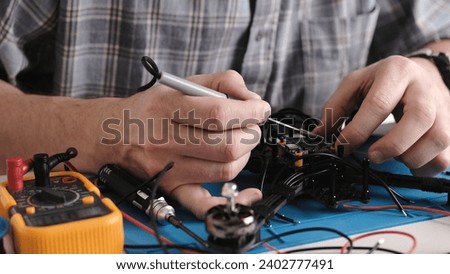 Repair Man Soldering Wires And Microchip Board On FPV Hobby Drone At Service Center Royalty-Free Stock Photo #2402777491