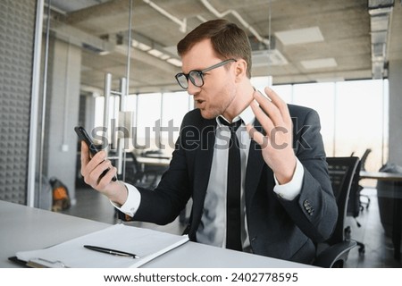 Angry businessman sitting at his desk and screaming at his employees