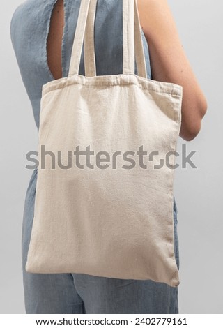 Carrying textile linen shopper, cotton tote bag, standing back view Royalty-Free Stock Photo #2402779161