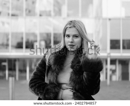 Monochrome film analog portrait of young caucasian woman posing in front of a modern building. Nostalgic mood and use of old cameras.