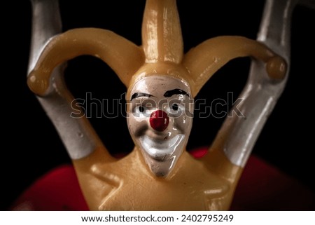 Creepy dirty toy jester in the dark. Scary face of a jester with a red nose on a black background