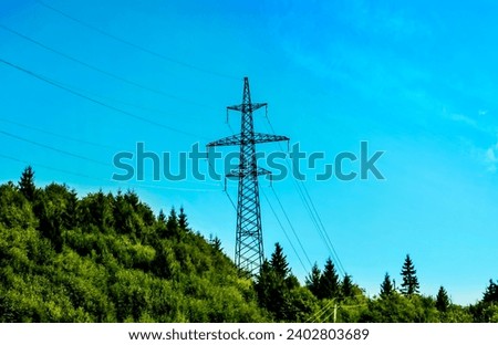 High-voltage power line against the background of the blue sky  in the mountains. Metal wires on a high-voltage tower transmit electricity long distances to cities. Ukraine