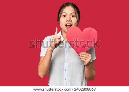 Chinese woman with red Valentine's heart having an idea, inspiration concept.