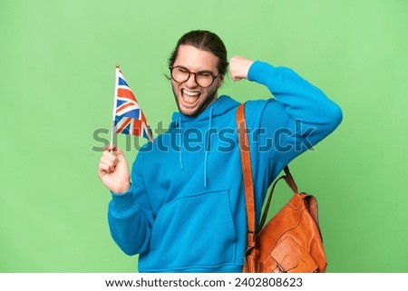 Young handsome man holding an United Kingdom flag over isolated background celebrating a victory Royalty-Free Stock Photo #2402808623