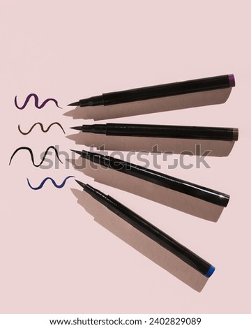 Four colors of liquid eyeliner next to swatches on pink background