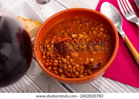 Delicious hearty stew of lentils with meat, smoked pork chorizo sausage and vegetables served in clay bowl. Authentic Spanish dish Royalty-Free Stock Photo #2402830783