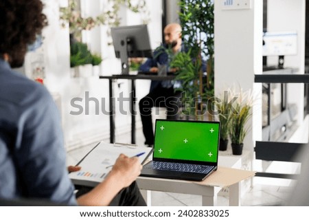 Employee analyzing financial report and working on laptop with chroma key green screen in business office. Executive manager checking data analysis plan and using portable computer