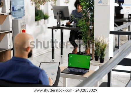 Businessman using laptop with chroma key green screen for data analysis and statistics. Executive working on project with graph and diagram on portable computer with blank display