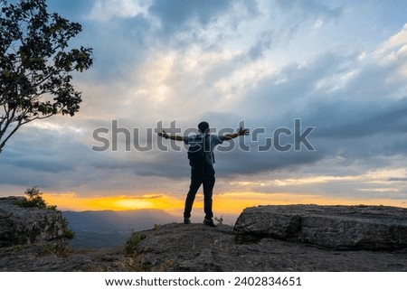 Tourist travel concept, man tourist stand on cliff of hill and see view of sunset sky background, beautiful view sunset on mountain high view, man wearing backpack for journey in nature outdoor tour