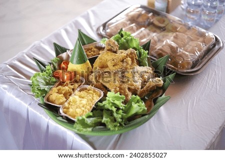 Traditional Indonesian food, nasi tumpeng, nasi kuning - with tempeh, egg, Chicken, Rice that is arranged in a cone is called tumpeng, The Nasi Tumpeng or Tumpengan Royalty-Free Stock Photo #2402855027