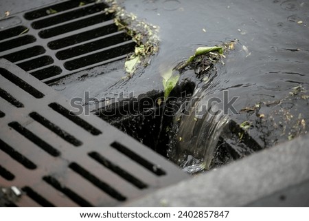 Rainwater is drained into an open storm system. Close-up. Royalty-Free Stock Photo #2402857847