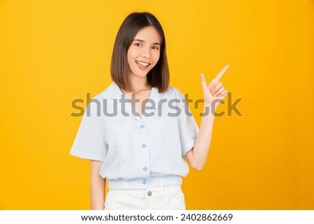 Happy smiling young woman hand pointing to the side, isolated on yellow background.