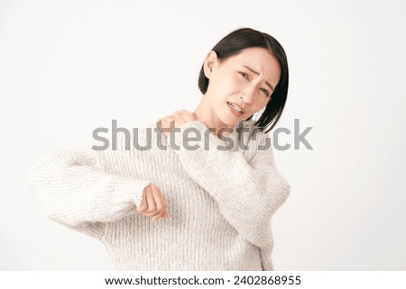 Asian middle aged woman having stiff shoulders in white background Royalty-Free Stock Photo #2402868955
