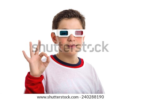 A Hispanic boy with smooth skin wears a pair of 3D Cinema paper eyeglasses with red and sky-blue lenses and makes ok sign with right hand while smiling