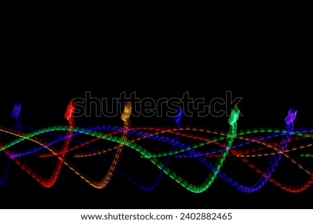 Light trails of bright multi colored holiday lights with a black background and copy space for text, created in camera with a slow shutter speed.