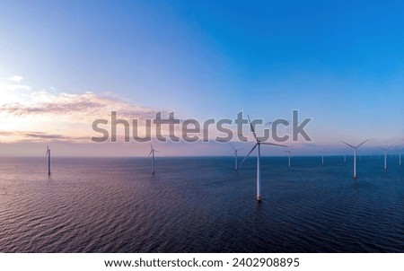 Windmill turbines generating electric green energy with a blue sky green energy concept in the Netherlands at sunset Royalty-Free Stock Photo #2402908895