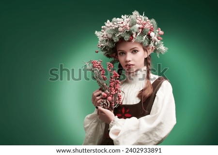 Portrait of a fairy-tale elf girl with berries on a green studio background. Fantasy character. Place for text.
