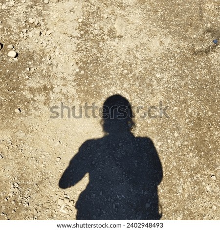 The portrait of a shadowy figure of a hiker on a plain in a town square.