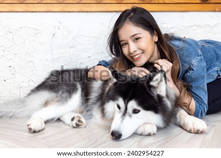Beautiful asian woman posing with lovely friendly siberian husky dog at home, companion animal, family, friendship, life balance concept.