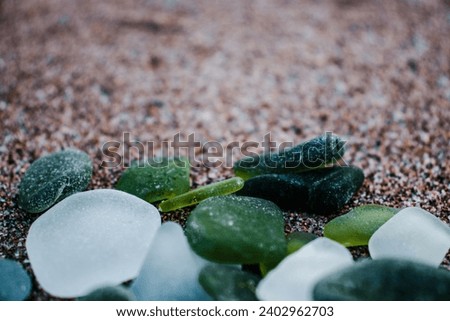 Sand beach and glass stones concept photo. Glass stones from broken bottles polished by the sea. Front view photography with blurred background. High quality picture for wallpaper, travel blog