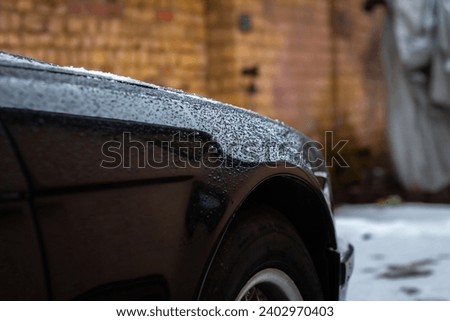 Drops of melted snow on an old black European car