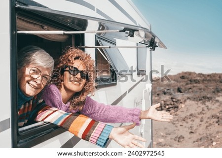 Travel and transport concept. Couple of smiling females friends or family at the window of the motorhome camper van enjoying road trip and vacation Royalty-Free Stock Photo #2402972545