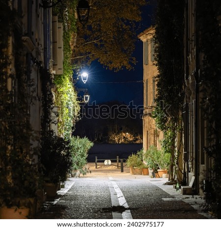 Narrow street in the old part of Arles, France, called La Roquette. Night picture, street lamps, chiaroscuro atmosphere.