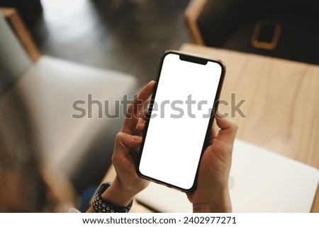 Close up view of a woman using blank screen smartphone in cafe.