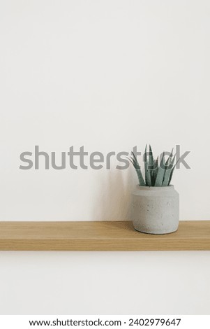 Artificial aloe flower in a gray pot on a wooden table in the decor of apartments in Scandinavian minimalist style with copy space