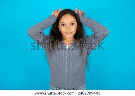 Funny Young beautiful teen girl shows horns, fingers on head gesture, posing silly and cute