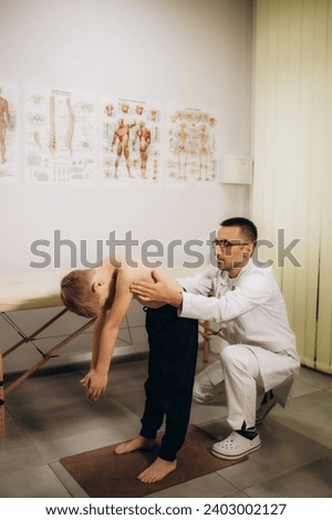 Orthopedist examining child's back in clinic. Scoliosis treatment. High quality photo