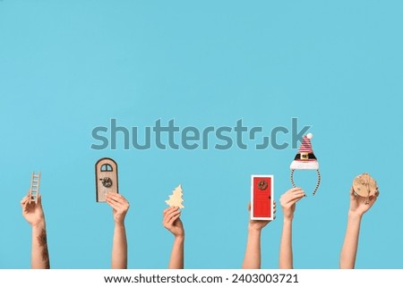 Female hands with wooden toys, elf hat headband and decorative doors on blue background