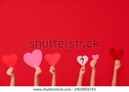 Female hands with different paper hearts on red background. Valentine's Day celebration