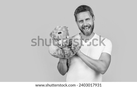 photo of positive guy holding valentine toy bear. guy hold valentine toy bear isolated on yellow