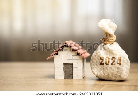 Money bag 2024 and miniature house. Family budget planning for next year. Mortgage rates and credit. Real estate fund concept. Refinance home. Royalty-Free Stock Photo #2403021851