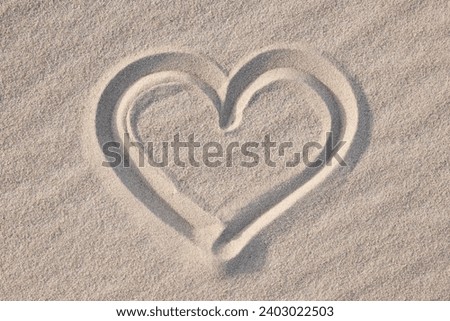 Shape of heart drawn on the sand, close up. Concept of love, passionate feelings, positive emotions, being in love