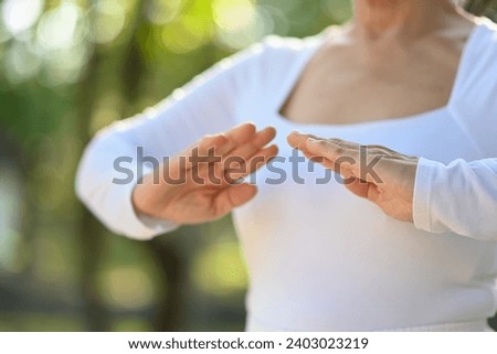 Cropped shot senior woman practicing Chi Kung or Tai Chi in nature. Healthy lifestyle concept. Royalty-Free Stock Photo #2403023219