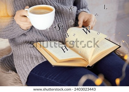 Woman with cup of coffee reading book with letters flying over it at home, closeup