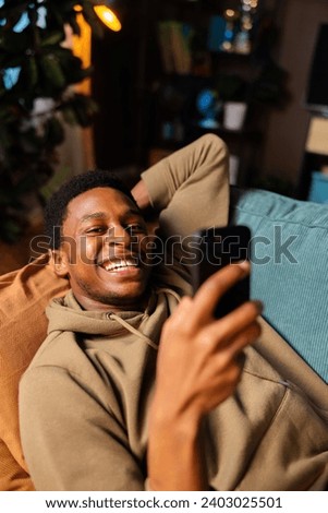 Happy African American dark skinned young professional taking a break from work, enjoying some downtime in his cozy living room resting relaxing freelance concept.