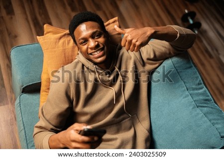 Young smiley attractive successful entrepreneur running his own business from home and working to build his brand through online marketing and outreach holdinf cellphone in hands. Royalty-Free Stock Photo #2403025509
