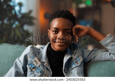 Portrait of delighted relaxed afro american woman smiling relaxing after hard work day job smiling wearing denim casual outfit sitting on the sofa at home.