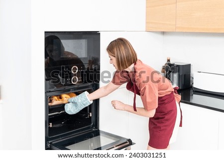 Young housewife baked delicious croissants for breakfast Royalty-Free Stock Photo #2403031251