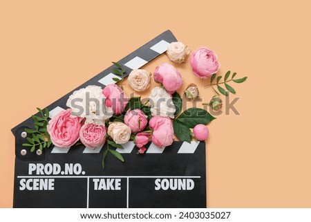 Composition with cinema clapperboard and beautiful flowers on color background, closeup