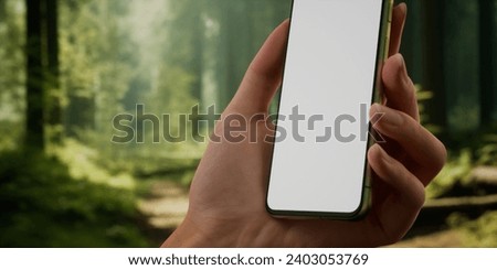 CU Woman using her phone outdoors in the forest during hiking or camping trip. Blank screen smartphone mockup, trail, travel, maps, photo application template