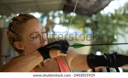 Sport woman in shooting range with bow. Outdoor archery training. Practice and training of archery in shooting range. Athlete keep wooden bow. Sportsman in shooting gallery aim an arrow to hit target Royalty-Free Stock Photo #2403055929